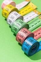 colorful measuring tapes top view on bright green background photo