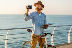 young attractive man traveling on bicycle by sea photo