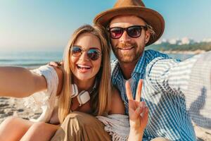 young attractive smiling happy man and woman in sunglasses lying on sand beach photo