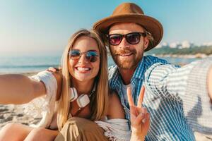 young attractive smiling happy man and woman in sunglasses lying on sand beach photo