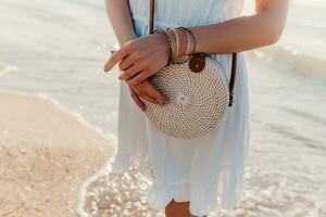woman in white dress with straw purse bag summer style on beach accessories photo