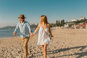 young attractive smiling happy man and woman running together on beach photo