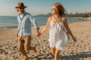 young attractive smiling happy man and woman running together on beach photo