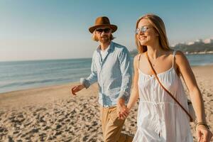 young attractive smiling happy man and woman running together on beach photo