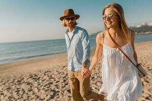 young attractive smiling happy man and woman running together on beach photo
