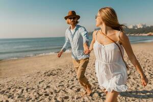 young attractive smiling happy man and woman running together on beach photo