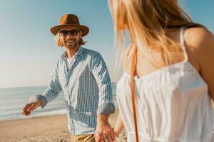 young attractive smiling happy man and woman running together on beach photo