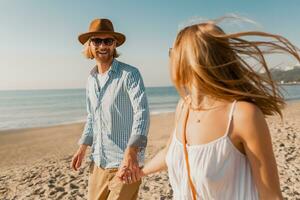 young attractive smiling happy man and woman running together on beach photo