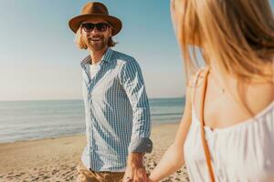 young attractive smiling happy man and woman running together on beach photo