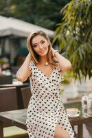 hermosa sonriente mujer vestido en blanco impreso vestir en calle café foto