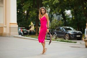 elegant attractive woman wearing pink sexy summer dress walking in street photo