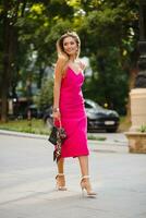 elegant attractive woman wearing pink sexy summer dress walking in street photo