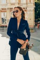 elegante atractivo mujer vistiendo azul elegante traje caminando en calle foto