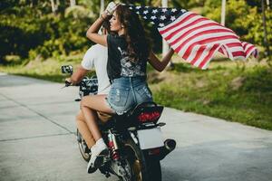 young couple in love, riding a motorcycle, hug, passion, free spirit, american flag photo