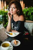 young stylish beautiful woman sitting at tropical resort cafe photo
