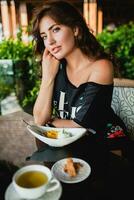 young stylish beautiful woman sitting at tropical resort cafe photo