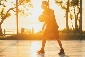 negro hombre haciendo Deportes, jugando baloncesto en amanecer, activo estilo de vida, soleado verano Mañana foto