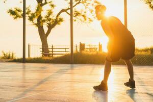 black man doing sports, playing basketball on sunrise, active lifestyle, sunny summer morning photo