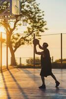 black man doing sports, playing basketball on sunrise, active lifestyle, sunny summer morning photo