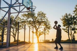 black man doing sports, playing basketball on sunrise, active lifestyle, sunny summer morning photo