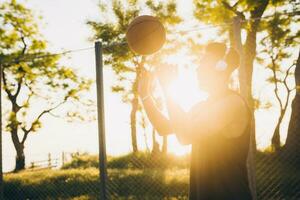 black man doing sports, playing basketball on sunrise, active lifestyle, sunny summer morning photo