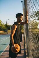 negro hombre haciendo Deportes, jugando baloncesto en amanecer, activo estilo de vida, soleado verano Mañana foto