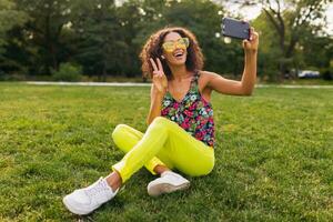 joven elegante negro mujer teniendo divertido en parque verano Moda estilo foto