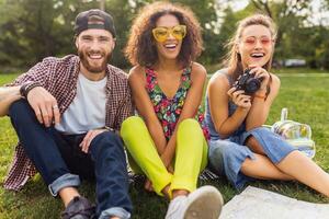 happy young company of talking smiling friends sitting park photo