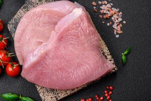 Raw turkey meat in the form of slices with salt, spices and herbs photo