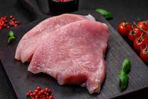 Raw turkey meat in the form of slices with salt, spices and herbs photo