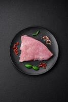 Raw turkey meat in the form of slices with salt, spices and herbs photo