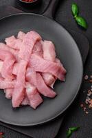 Raw turkey meat in the form of slices with salt, spices and herbs photo