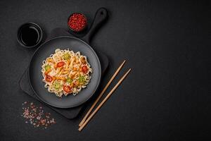 Delicious Asian cuisine dish with rice noodles, peppers, mushrooms and spices photo