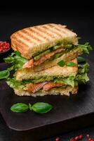 Delicious crispy sandwich with toast, salmon, avocado, tomatoes, salt, spices and herbs photo