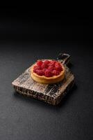 Delicious fresh sweet round tart with ripe raspberries and cream photo