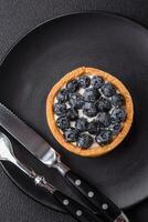 Delicious fresh sweet round tart with ripe blueberries and cream photo