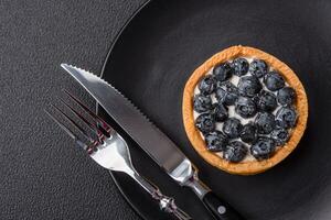 Delicious fresh sweet round tart with ripe blueberries and cream photo