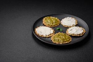 Round snacks with crispy chips or crackers with cream cheese and pesto photo