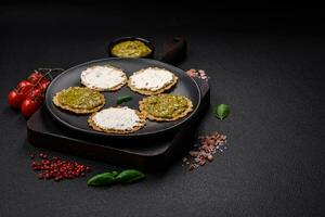 Round snacks with crispy chips or crackers with cream cheese and pesto photo