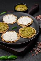 Round snacks with crispy chips or crackers with cream cheese and pesto photo