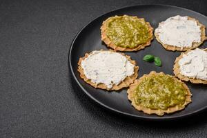 Round snacks with crispy chips or crackers with cream cheese and pesto photo