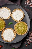 Round snacks with crispy chips or crackers with cream cheese and pesto photo