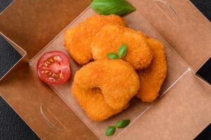 Delicious fresh crispy chicken nuggets on a dark concrete background photo