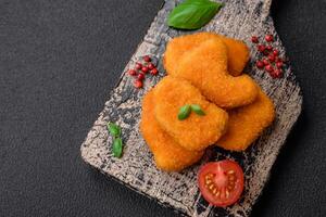 Delicious fresh crispy chicken nuggets on a dark concrete background photo