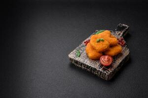 Delicious fresh crispy chicken nuggets on a dark concrete background photo