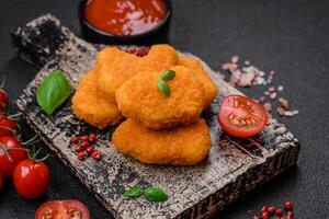 Delicious fresh crispy chicken nuggets on a dark concrete background photo