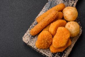 Delicious nuggets, sticks and balls of mozzarella and parmesan cheese with salt and spices photo