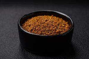 Crystals of brown Svan salt with spices in a black bowl photo