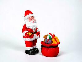 Miniature Santa figure with gift bag on white background photo