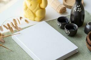 Book mockup design. Blank white book on dining table in asian style with tableware photo